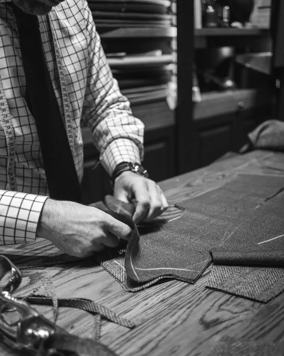A tailor marking cloth on a wooden cutting table