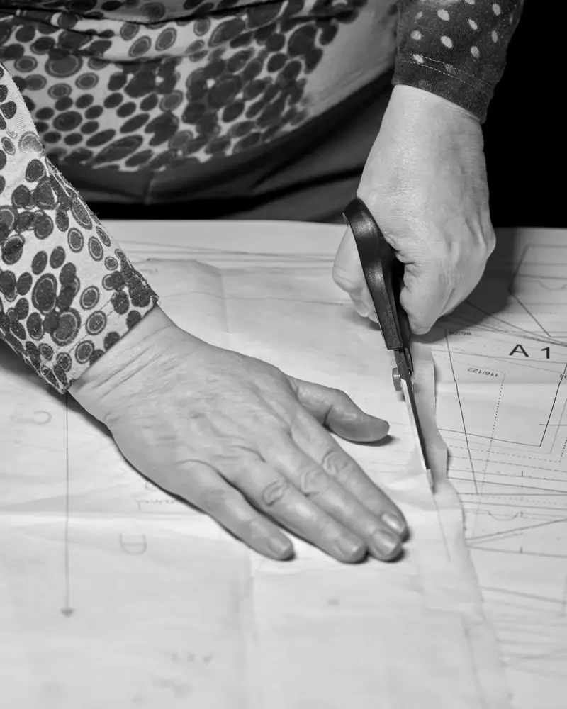 Hands cutting a paper pattern with tailor's shears